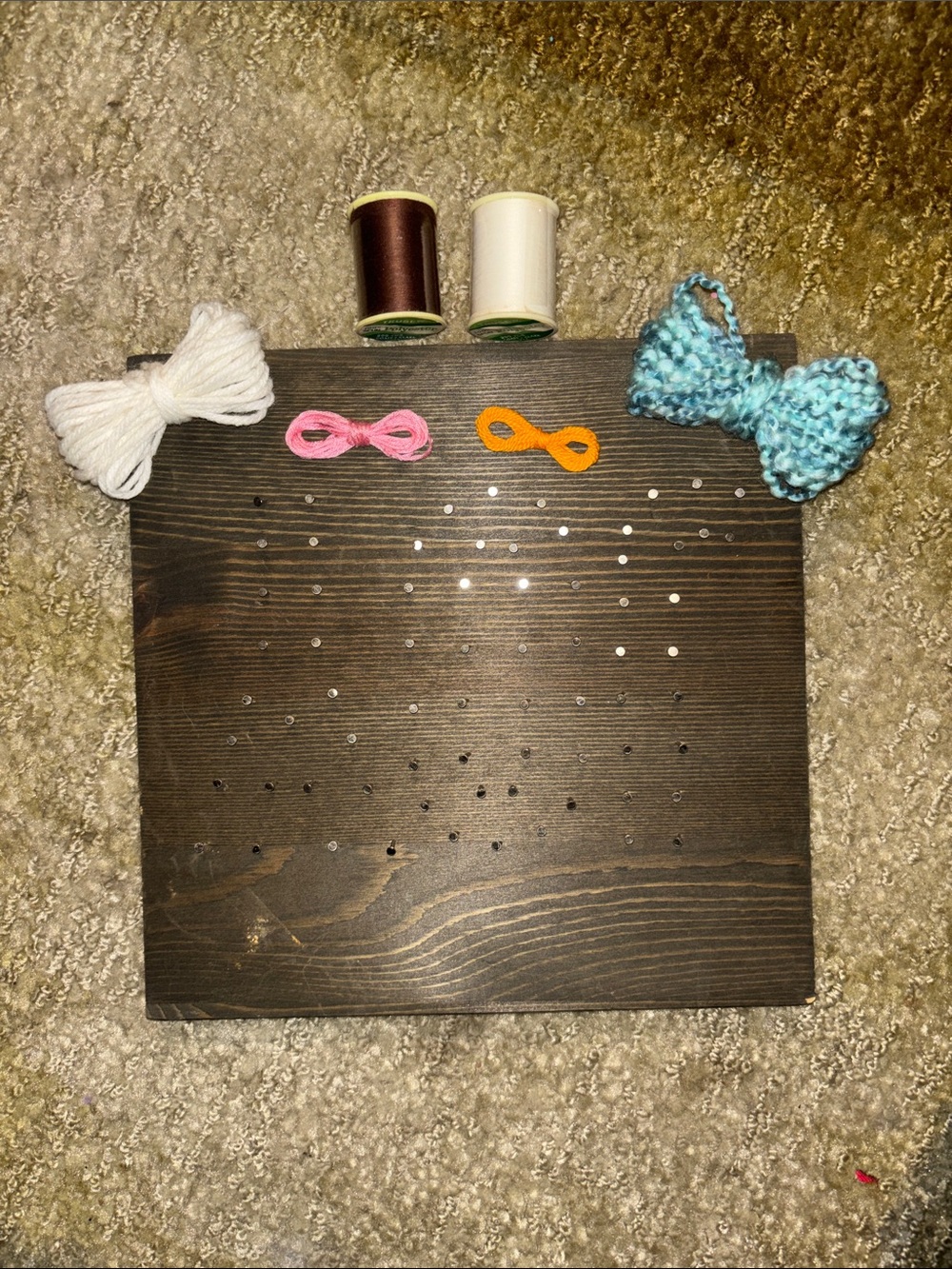 Wooden Pegboard Display with Yarn Bows and Thread Spools